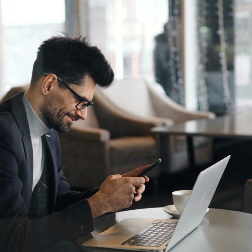 Une homme souriant qui regarde son smartphone