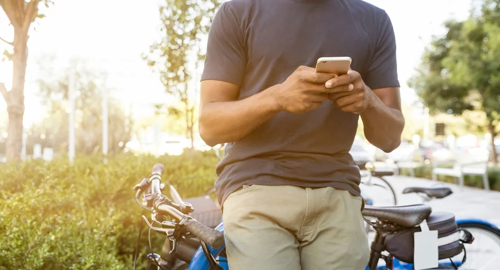 1. Homme tenant un smartphone appuyé sur un vélo pendant la journée