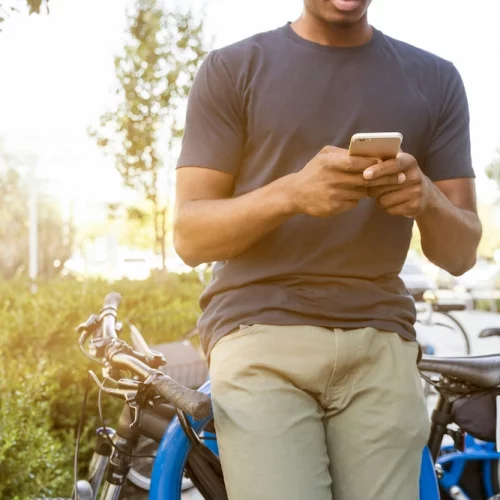 1. Homme tenant un smartphone appuyé sur un vélo pendant la journée