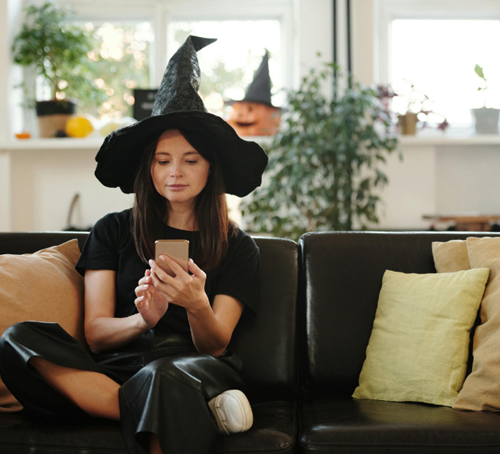 Une femme déguisée pour Halloween recevant un SMS sur son smartphone