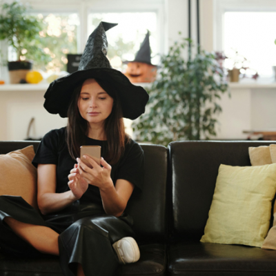 Une femme déguisée pour Halloween recevant un SMS sur son smartphone