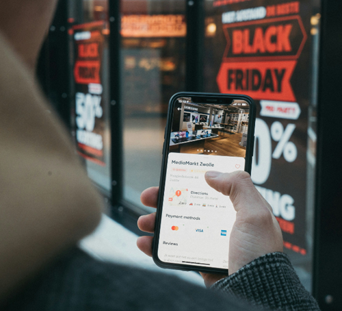 Une personne tenant son smartphone affichant des infos sur le Black Friday