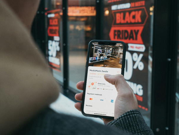 Une personne tenant son smartphone affichant des infos sur le Black Friday