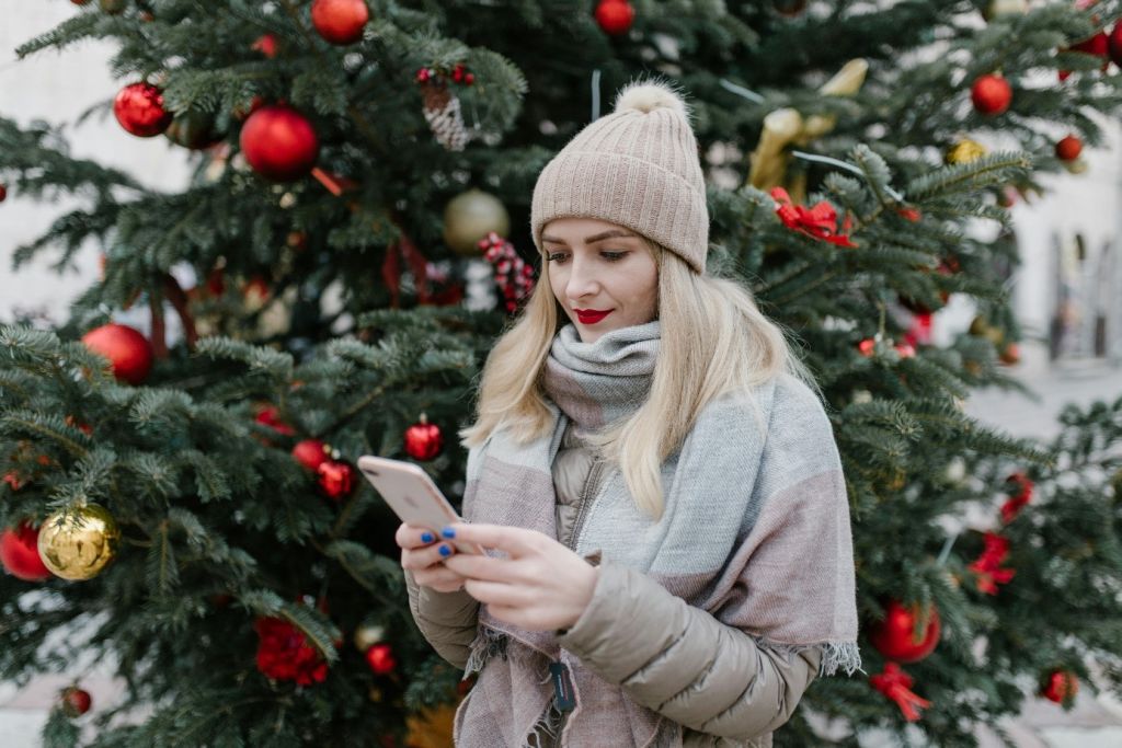 Une femme devant un sapin de Noël recevant une offre par SMS