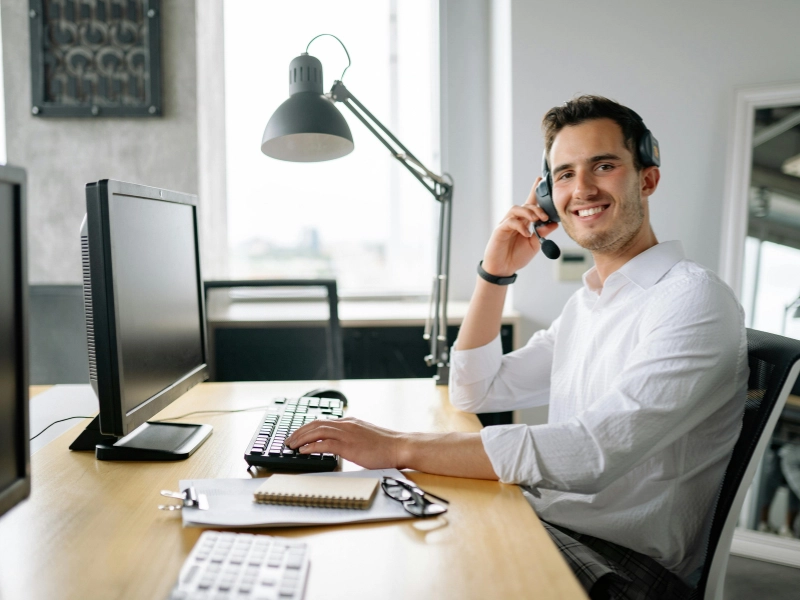 Un homme souriant devant son écran d’ordinateur